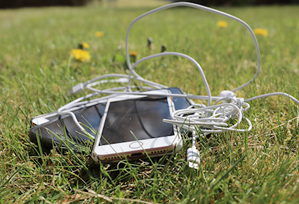 Mobiltelefon med ledning liggende i gresset
