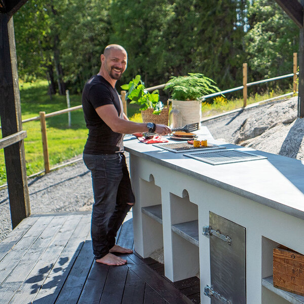 Björn står ved utekjøkkenet sitt