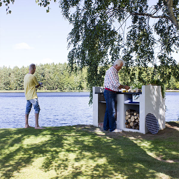 Mann som griller ved utegrillen sin